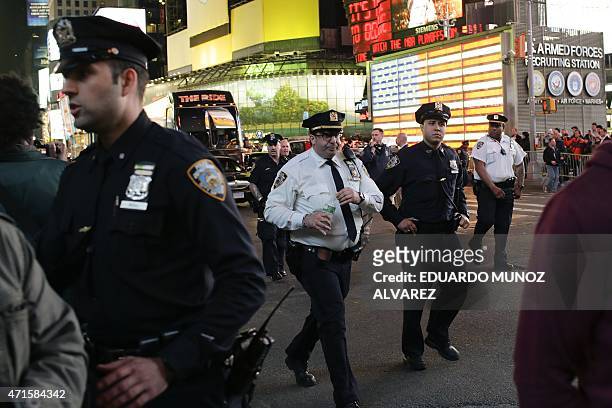 Officers stand guard while demonstrators march through Times Square during a protest April 29, 2015 in New York, held in solidarity with...