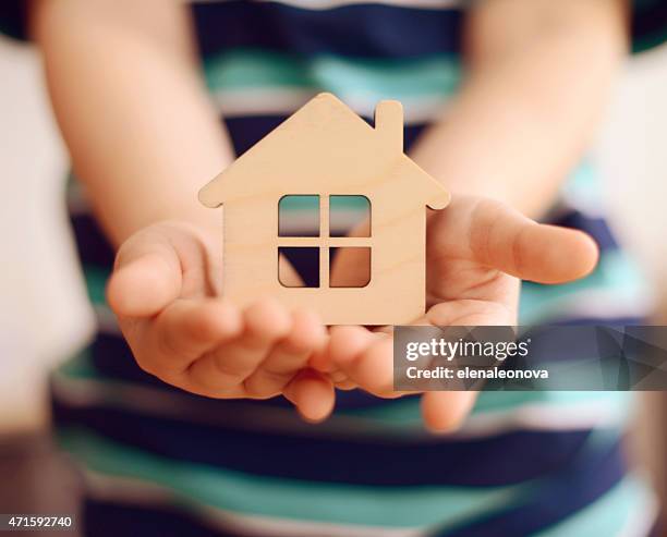 little boy tiene entre manos pequeña casa de juguete - seguro del hogar fotografías e imágenes de stock