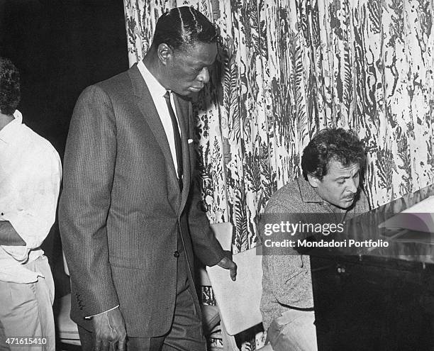 Italian singer-songwriter Domenico Modugno playing piano beside American singer and pianist Nat King Cole . 1950s