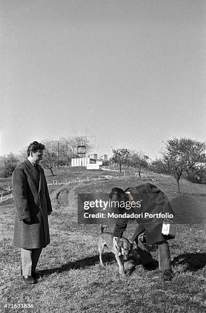 "Italian brothers and radio amateurs Achille and Giovanni Battista Judica Cordiglia playing with a dog in front of Bert Tower, their space listening...