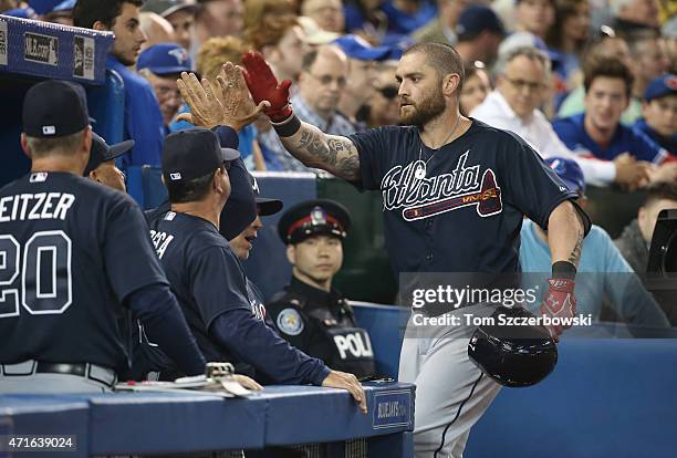 Jonny Gomes of the Atlanta Braves is congratulated by manager Fredi Gonzalez and bench coach Carlos Tosca and teammates in the dugout after hitting a...