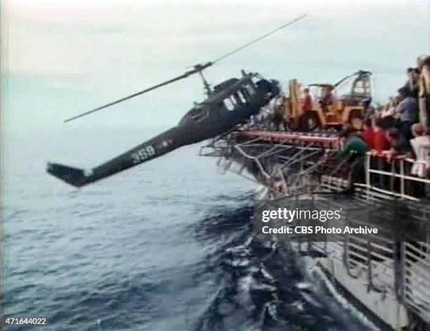 April 29, 1975: US Navy personnel of the USS Blue Ridge push a helicopter into the South China Sea off the coast of Vietnam in order to make room for...