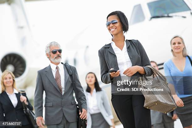 group of powerful business executives deboarding private company jet - airport departure board stock pictures, royalty-free photos & images