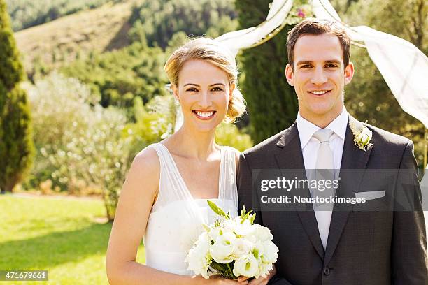newlywed couple standing in garden - front on groom and bride stock pictures, royalty-free photos & images