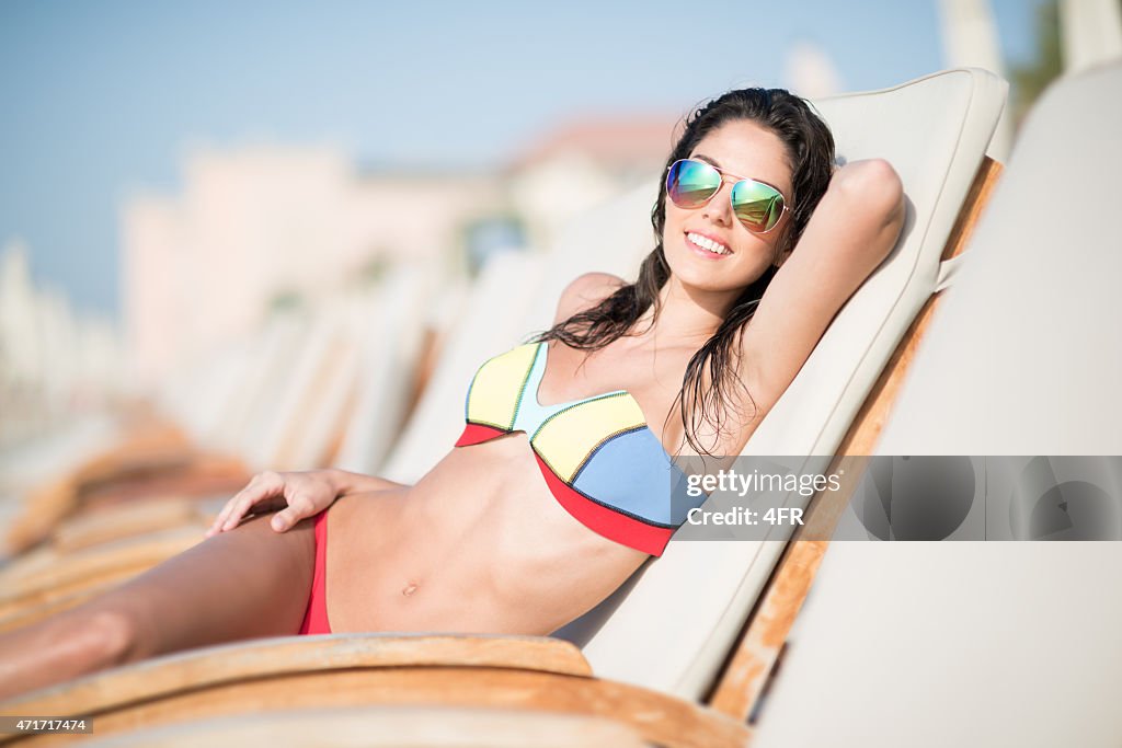 Happy Woman enjoying her beach vacation in a sun chair