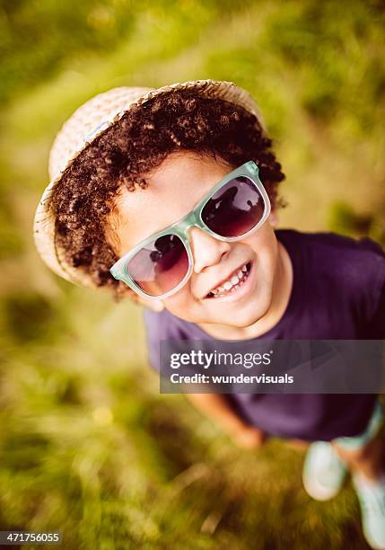 little boy smiling and looking up in meadow - black hat stock pictures, royalty-free photos & images
