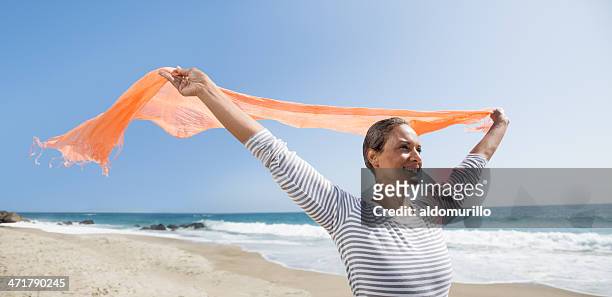 happy senior woman enjoying the wind - woman flying scarf stock pictures, royalty-free photos & images