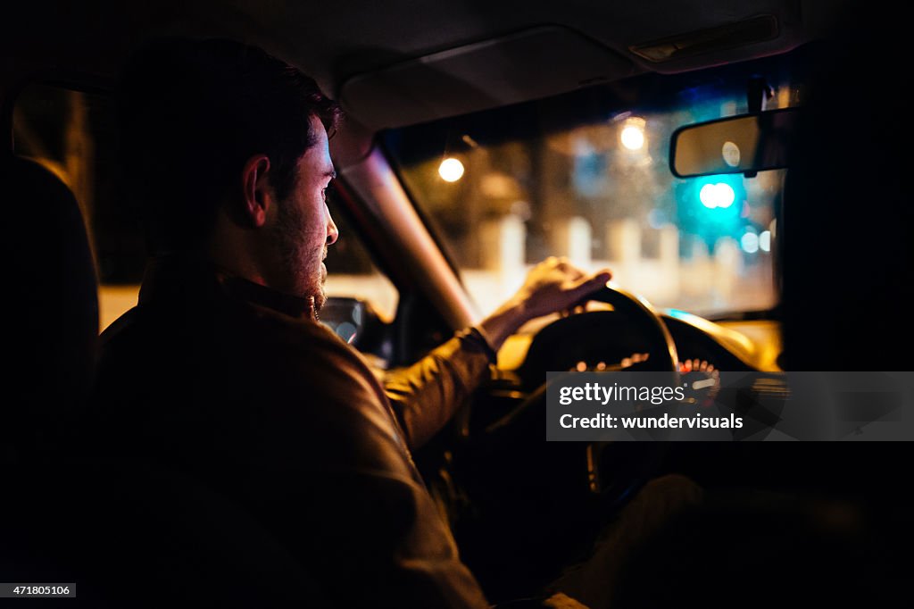 Hombre en automóvil, taxi privado a través de calles de la ciudad por la noche