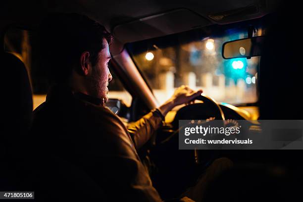 uomo di guidare un taxi privato attraverso le vie di città di notte - taxi foto e immagini stock