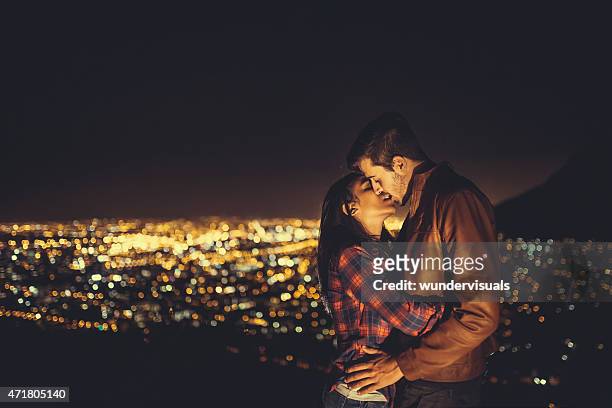 paar küssen mit lichtern der stadt im hintergrund. - auto küssen stock-fotos und bilder