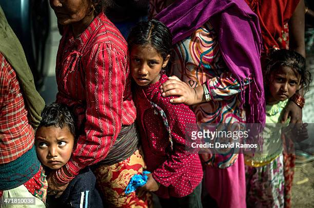 Victims of the earthquake queue on a road as they wait to receive food and goods at an aid distribution point on May 1, 2015 in Bhotechaur, Nepal. A...