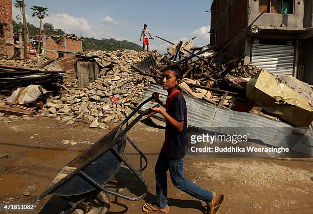 Nepalese earthquake victim young boy carries wheelbarrow for remove to debris from his collapsed house on May 1, 2015 in Kavrepalanchowk, Nepal. A...