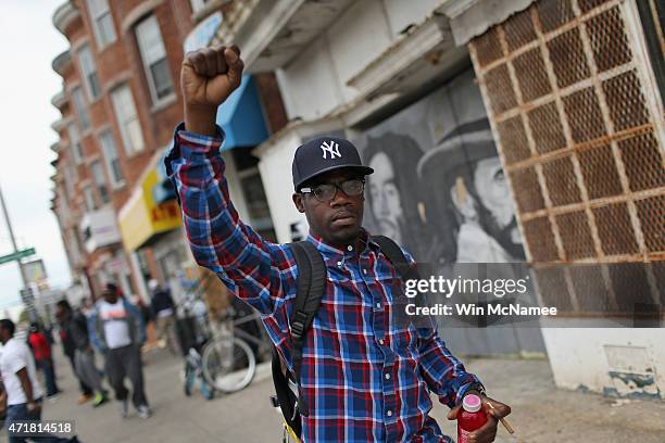 Man raises his fist while walking down the street after Baltimore authorities released a report on the death of Freddie Gray on May 1, 2015 in...