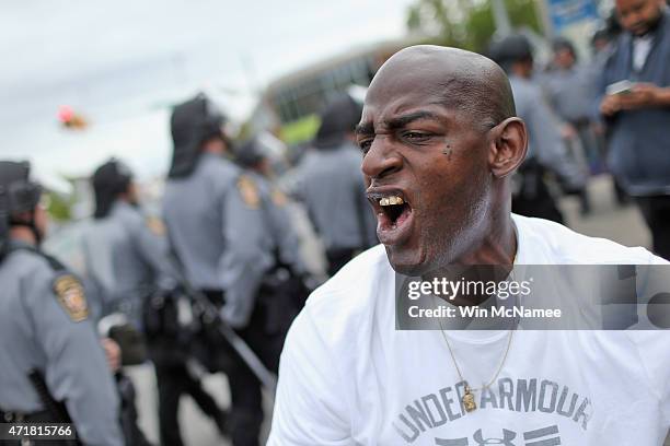 Man shouts "Manslughter not enough, should have been murder" while riot poilice patrol in the background after Baltimore authorities released a...