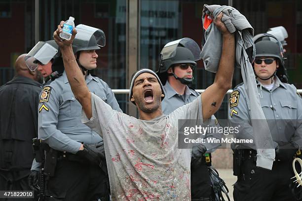 Lorning Cornish shouts after Baltimore authorities released a report on the death of Freddie Gray while police in riot gear stand guard on May 1,...