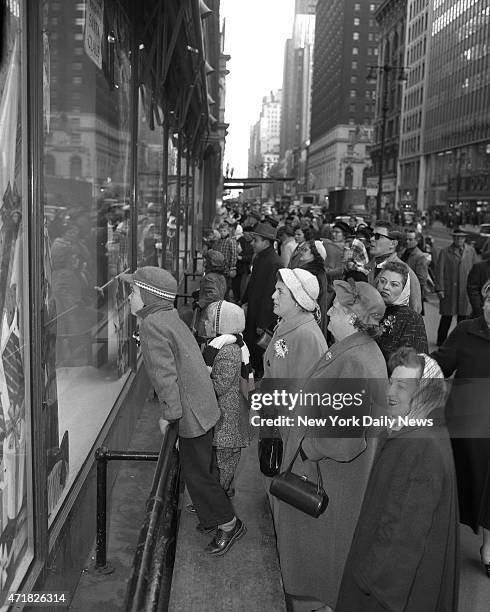 Christmas crowds along 34th St. With their noses pressed against the glass, children window shop with their family at Macy's in Manhattan