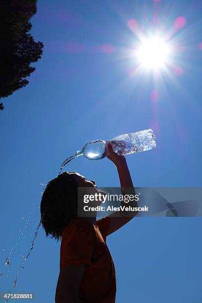 child pouring water on self silhouetted on blue - hot boy body stock pictures, royalty-free photos & images