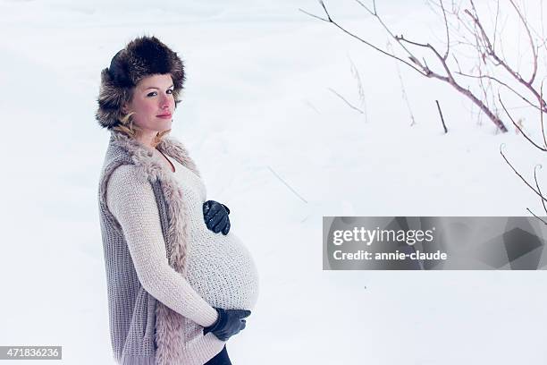 pregnant woman with fur hat posign in a snowy landscape - fur glove stock pictures, royalty-free photos & images