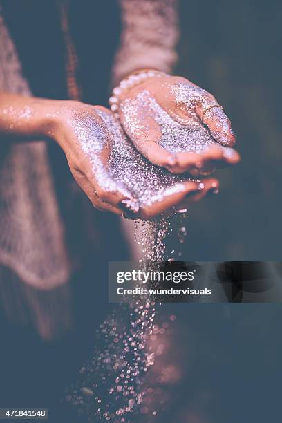 hands with silver glitter falling from them - cechy stockfoto's en -beelden