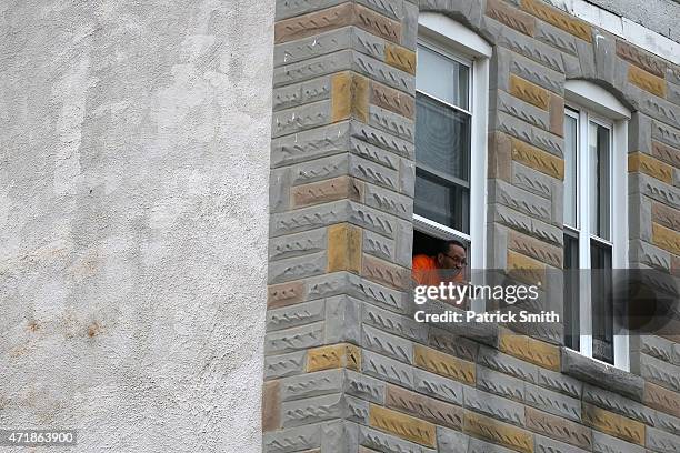 Man take pictures from a window as protesters march after Baltimore authorities released a report on the death of Freddie Gray on May 1, 2015 in...