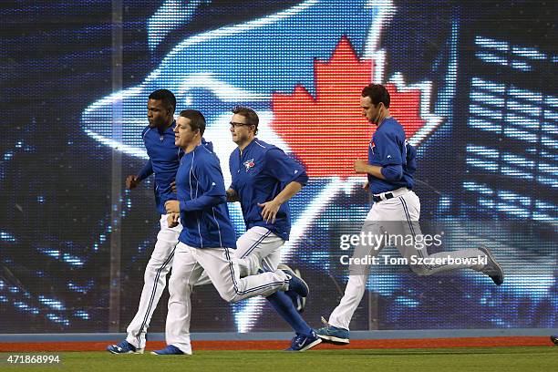 Miguel Castro of the Toronto Blue Jays and Aaron Loup and Brett Cecil and Jeff Francis jog in the outfield during batting practice before the start...