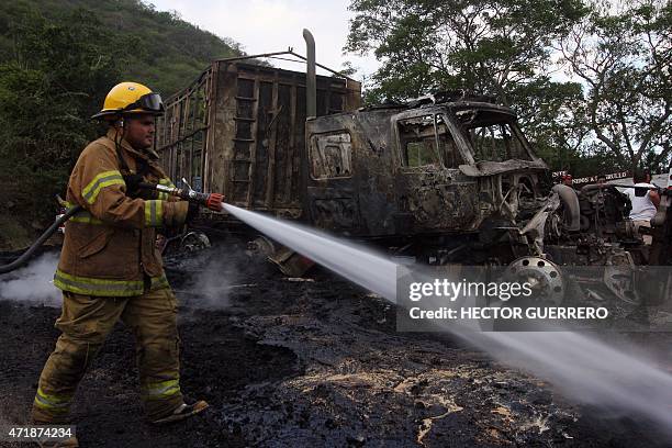 Firefighters work on a burned truck in the Guadalajara - Autlan highway, Jalisco state, Mexico, on May 1, 2015. More than a dozen vehicles were set...