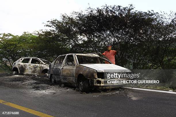 Man gestures next to burned cars in Guadalajara - Autlan highway, Jalisco state, Mexico, on May 1, 2015. More than a dozen vehicles were set on fire...