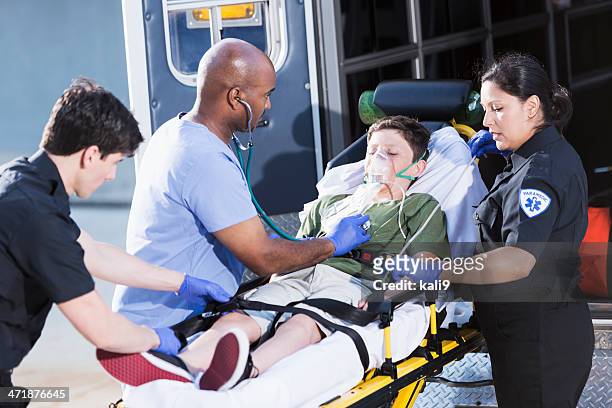 doctor and paramedics helping child - accident hospital stockfoto's en -beelden