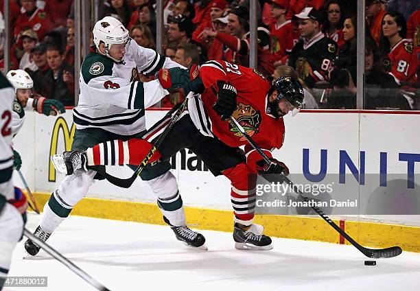 Johnny Oduya of the Chicago Blackhawks controls the puck as he is shoved by Charlie Coyle of the Minnesota Wild in Game One of the Western Conference...