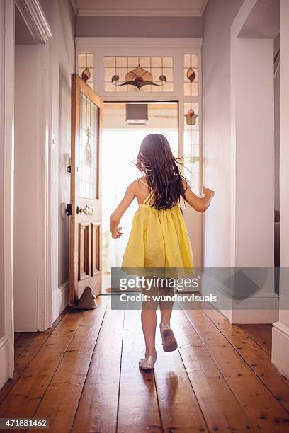 little girl running happily to an open front door - yellow dress stock pictures, royalty-free photos & images