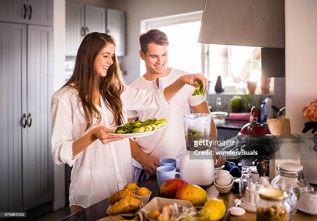 Couple à l'aide d'un mélangeur pour prendre un petit déjeuner équilibré