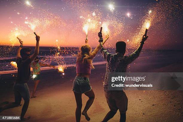 amigos correr em uma praia com fogos de artifício - festa na praia imagens e fotografias de stock