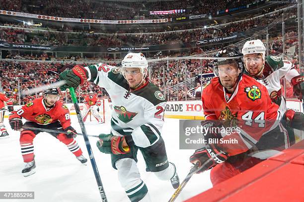 Kimmo Timonen of the Chicago Blackhawks skates around the boards against Nino Niederreiter and Chris Stewart of the Minnesota Wild in Game One of the...