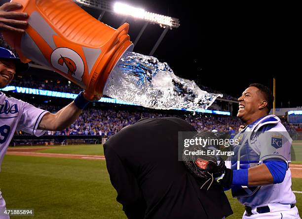 Salvador Perez of the Kansas City Royals takes cover behind Fox Sports Kansas City's Joel Goldberg as he avoids being hit by a water douse from...