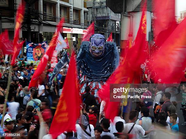 Protesters carrying flags walk past an effigy depicting Philippine President Benigno Aquino III as a grim reaper, during a rally near Malacanang...