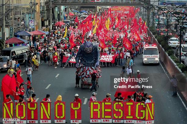 An ambulance drives past marching protesters, center right, as protesters march along Quiapo district, alongside an effigy depicting Philippine...