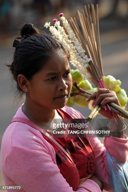 Cambodian vendor holds incense sticks and flowers as she waits for customers during the Visak Bochea at the Oddong mountain in Kandal province on May...