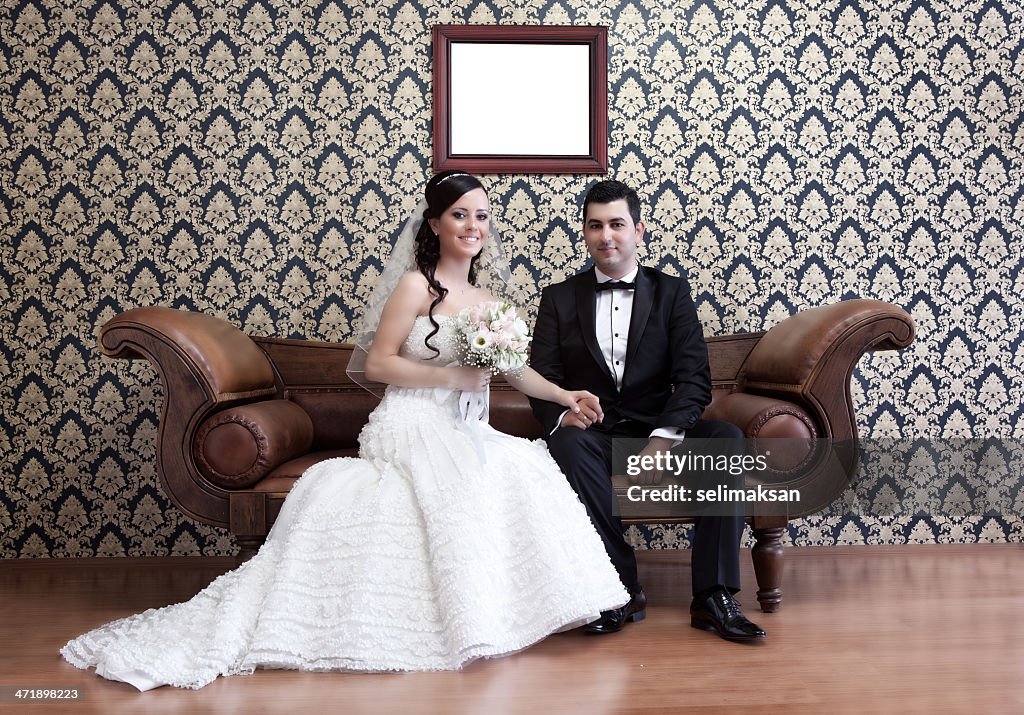 Happy bride and groom sitting on sofa