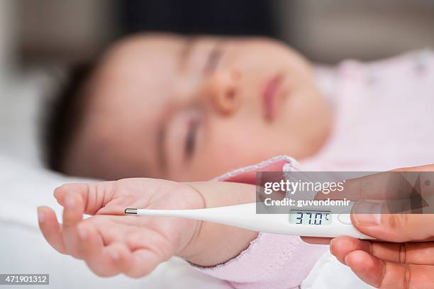 mother checking baby's temperature - fever chills stock pictures, royalty-free photos & images