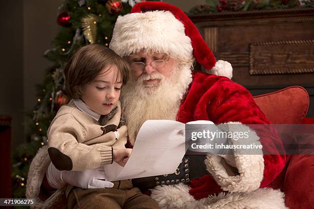 boy going over naughty nice list with santa - naughty santa stock pictures, royalty-free photos & images