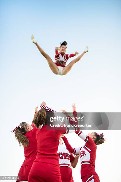 cheerleaders throw up a girl in the air - cheerleader stock pictures, royalty-free photos & images