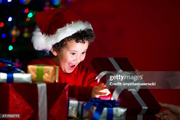 excited child opening a gift under the christmas tree - child christmas costume stock pictures, royalty-free photos & images