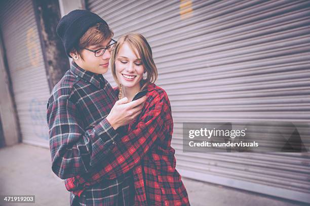 embracing couple looking at cell phone - tcs stock pictures, royalty-free photos & images