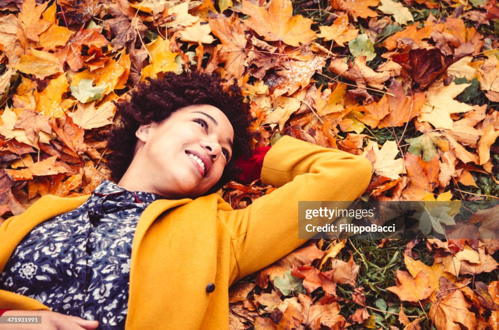 Young woman lying down on autumn leaves