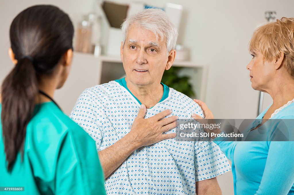 Senior patient in hospital explaining pain to doctor or nurse