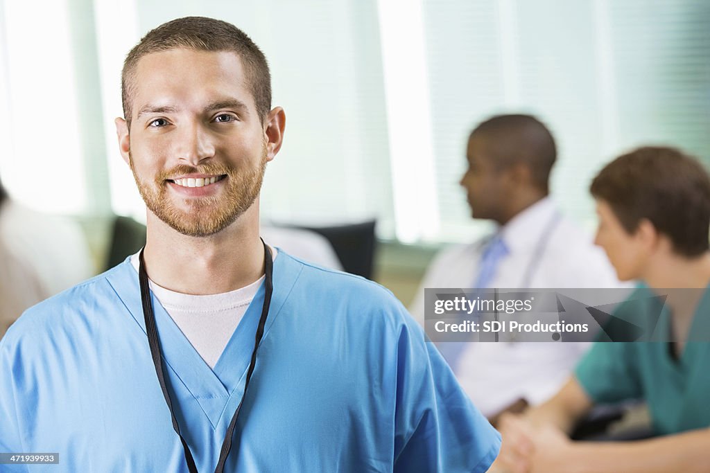 Friendly male nurse or physician in hospital staff meeting