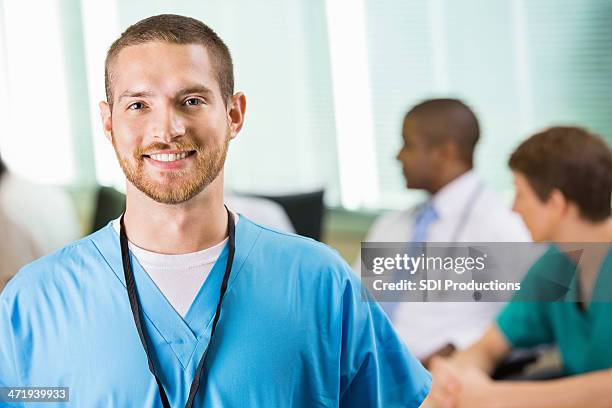 friendly male nurse or physician in hospital staff meeting - male medical professional stock pictures, royalty-free photos & images