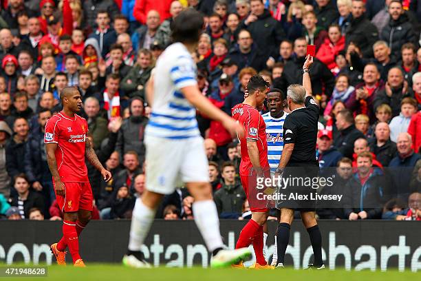 Nedum Onuoha of QPR is shown the red card by referee Martin Atkinson during the Barclays Premier League match between Liverpool and Queens Park...