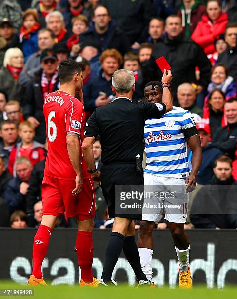 Nedum Onuoha of QPR is shown the red card by referee Martin Atkinson during the Barclays Premier League match between Liverpool and Queens Park...