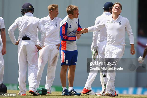 Gary Ballance of England is treated by physio Craig de Weymarn after being hit on the hand whilst fielding at silly mid onshort leg during day two of...